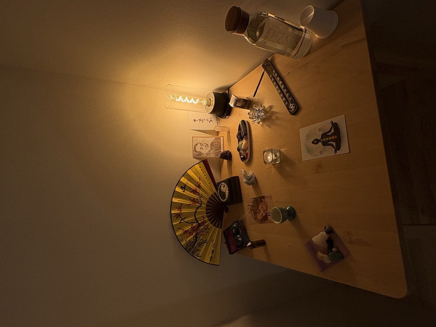 A quiet Reiki altar with a folding fan, crystals, and warm candlelight