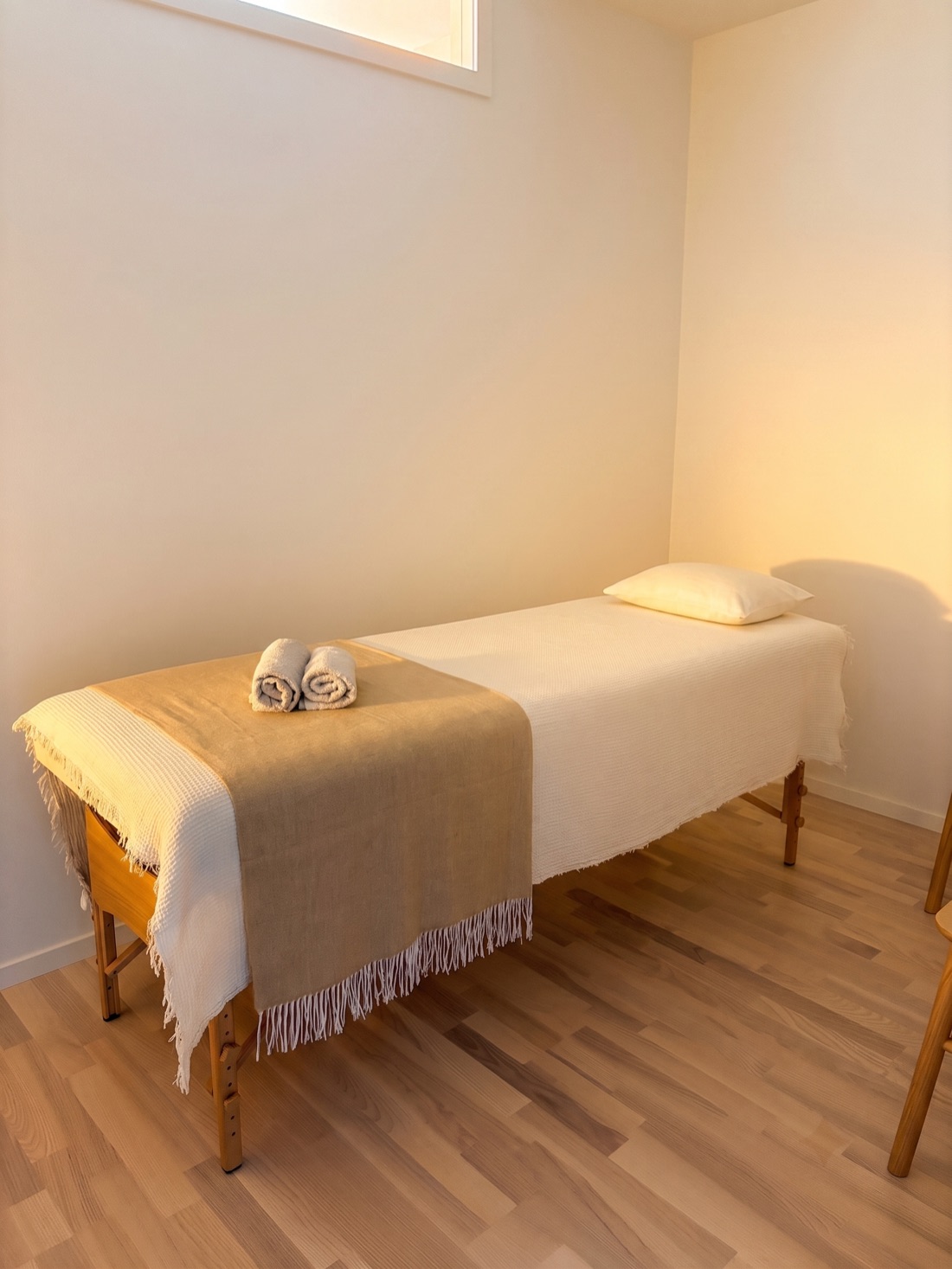 A treatment table dressed in soft, warm-toned linens and folded towels